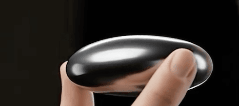Sweet Pea AI earpiece — a dark chrome pebble-shaped device held in hand